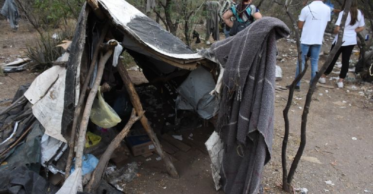 Su casa son palos levantados cubiertos con cobijas, hule negro y lonas