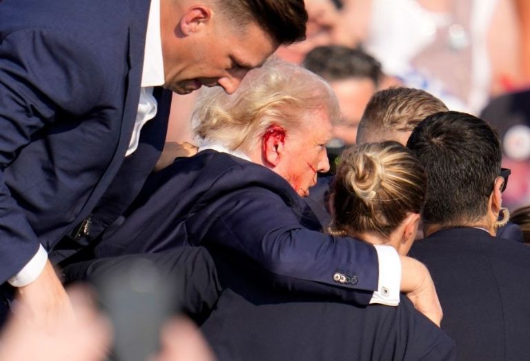 Donald Trump escoltado hacia un vehículo fuera del escenario