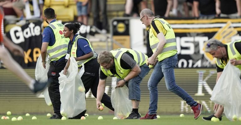 Trabajadores recogen pelotas arrojadas a la cancha