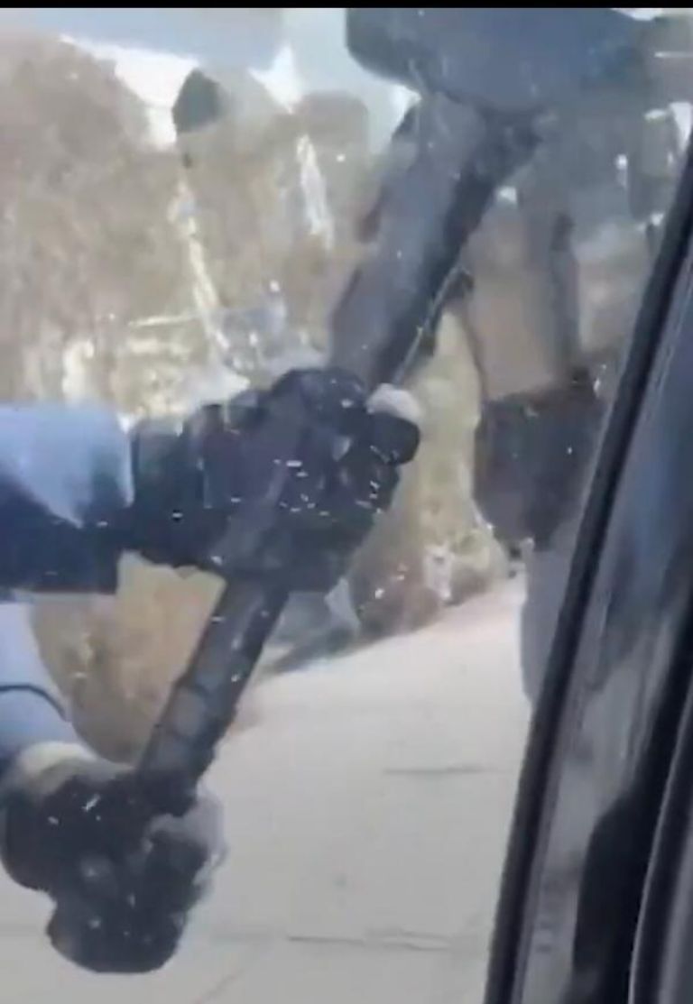 Agente de ICE justo en el momento en que golpea el vidrio con un martillo 