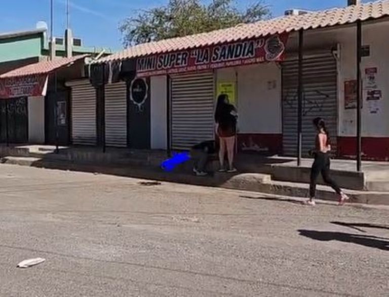 Una mujer abraza a la víctima que yace sobre la banqueta