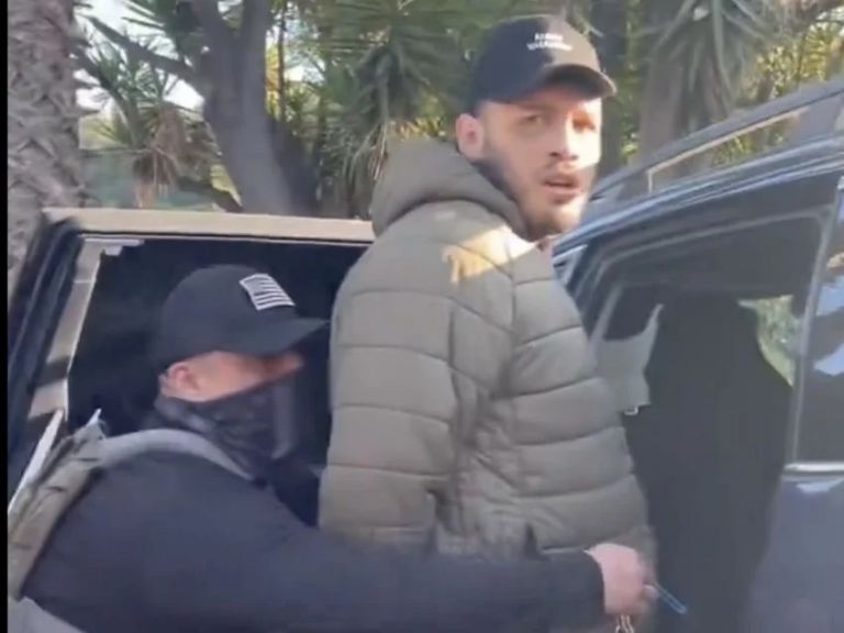 Un elemento de ICE se encuentra colocándole las esposas e inspeccionado su vehiculo