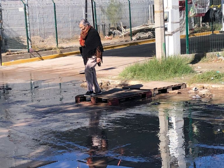 Adultos mayores cruzando aguas negras